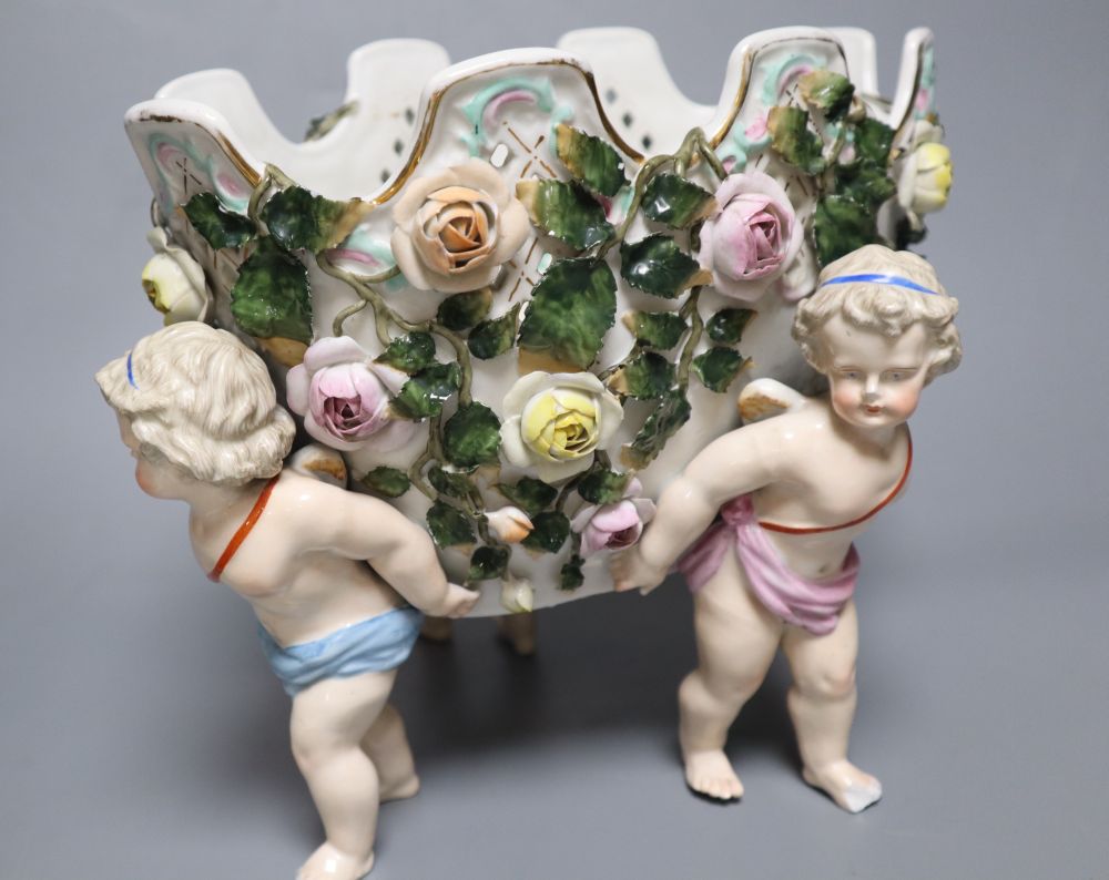 A Meissen style flower-encrusted reticulated oval porcelain jardiniere with cherub supports and three other items,